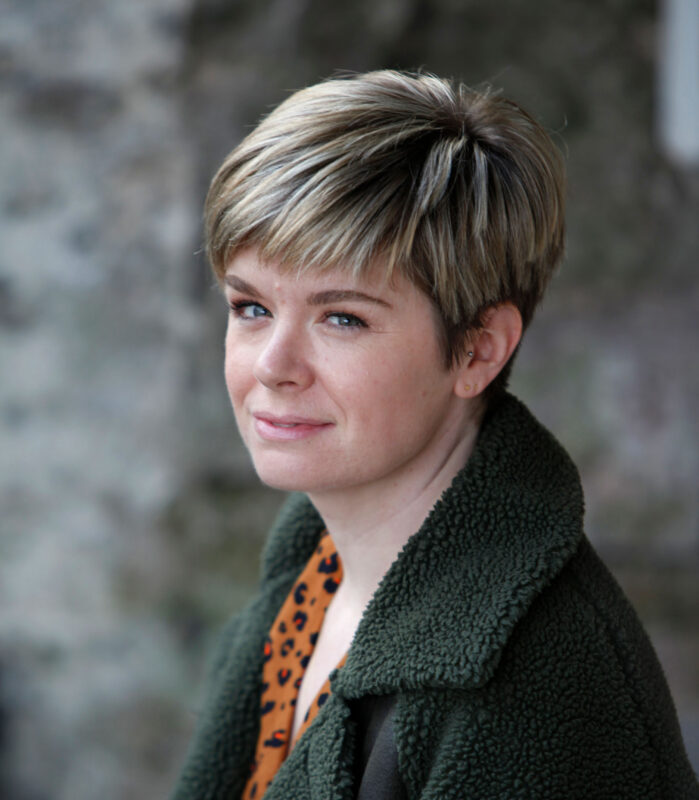 Portrait of Rhian Hughes, wearing a dark green jacket and looking slightly towards the camera. 